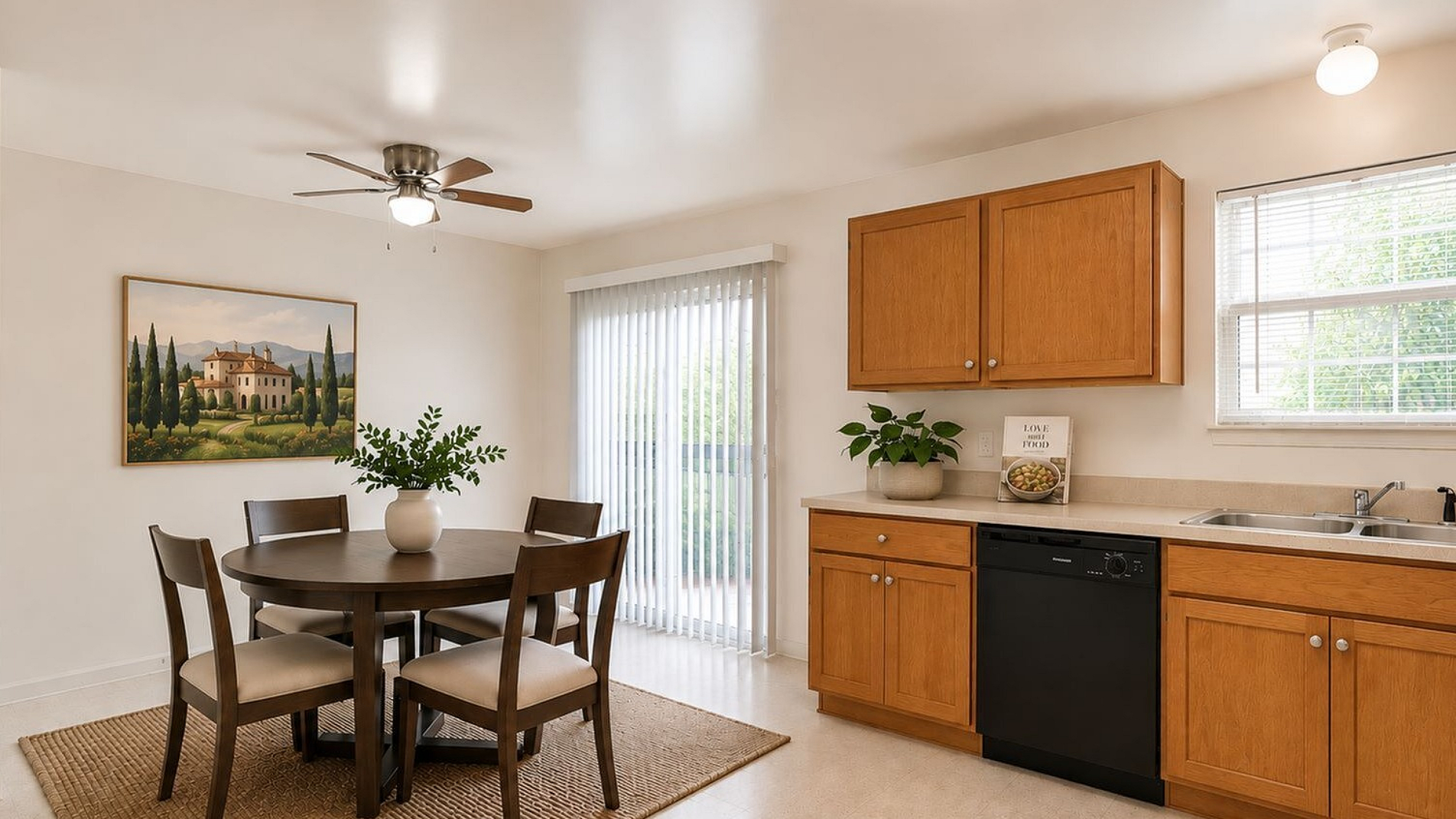 Bright and inviting kitchen and dining area featuring natural light, wooden cabinetry, a cozy round dining table, and elegant decor.