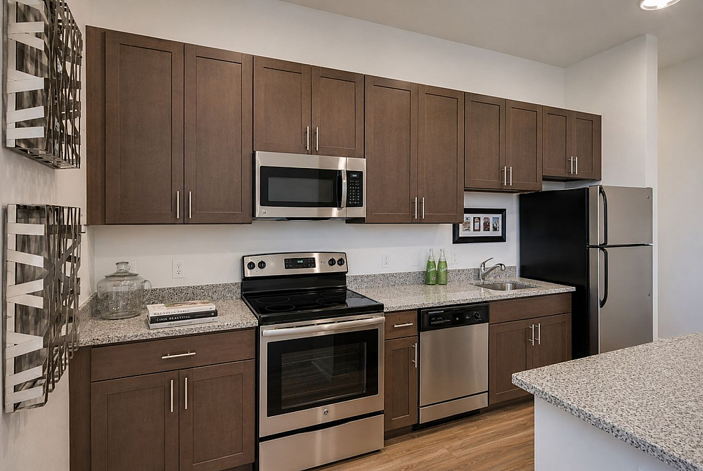 Modern kitchen with sleek stainless steel appliances, elegant dark wood cabinetry, and stylish granite countertops.