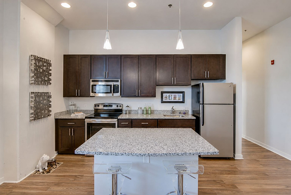 Elegant modern kitchen with sleek granite countertops, stainless steel appliances, and stylish pendant lighting.