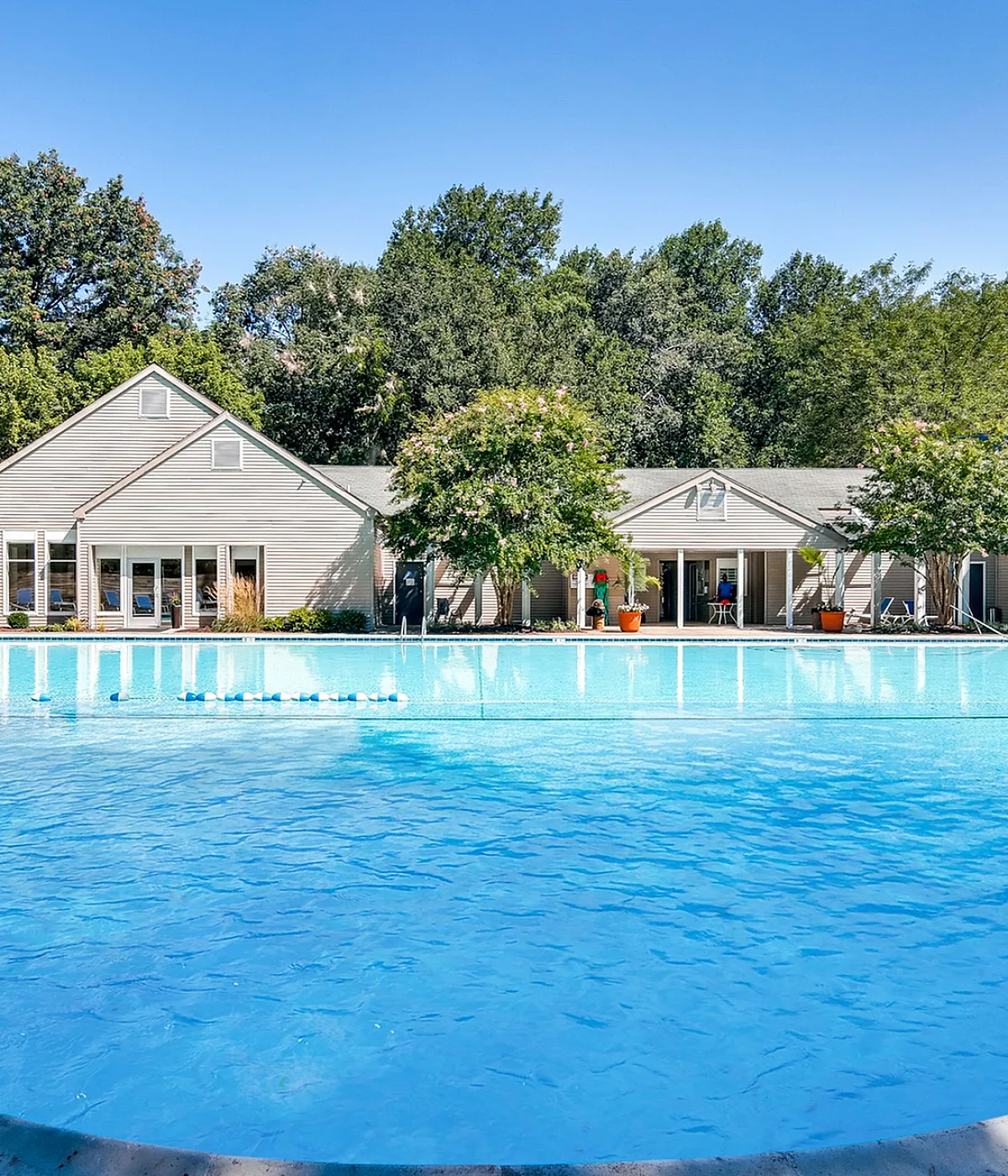 Inviting outdoor swimming pool with scenic views of lush greenery and charming residential cottages, perfect for relaxation and leisure.