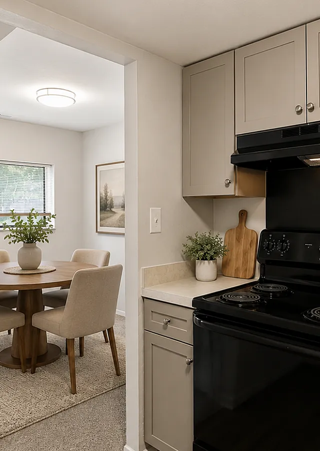 Chic kitchen with modern black appliances, light cabinetry, and a cozy dining area with a round wooden table and upholstered chairs, perfect for intimate gatherings.