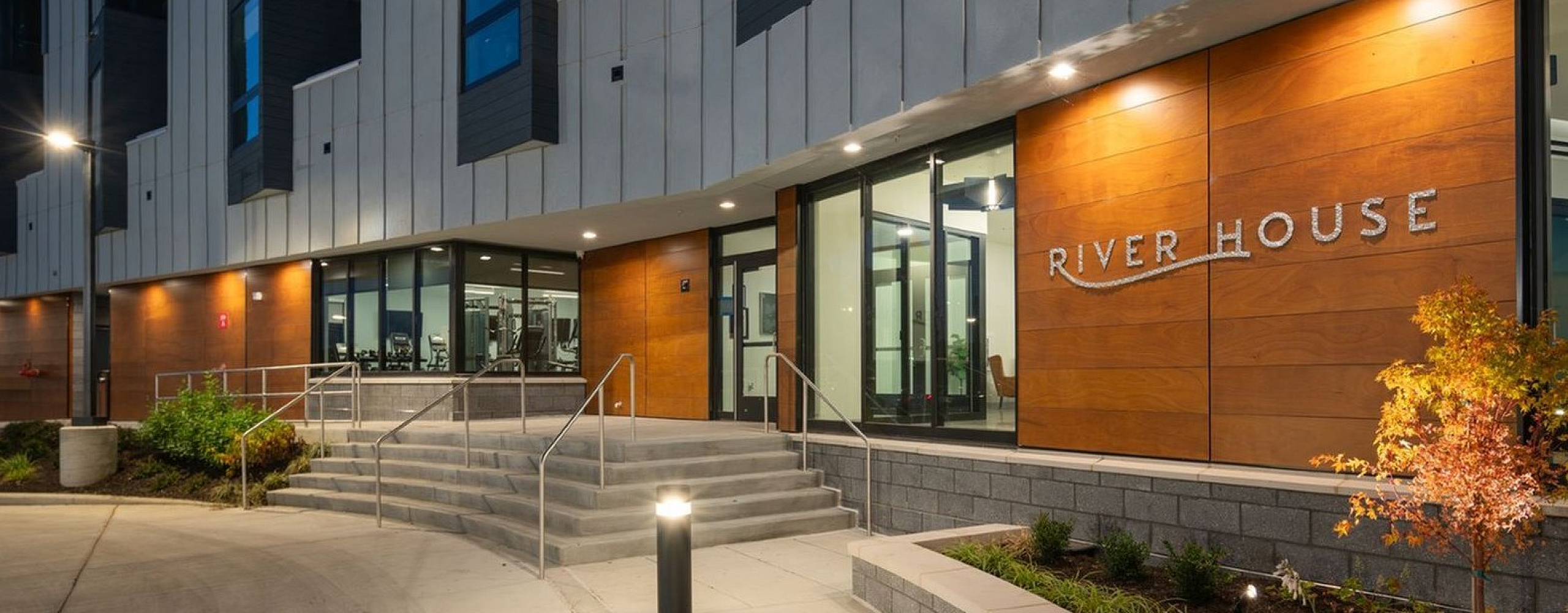 Modern apartment building entrance at dusk featuring elegant lighting and stylish design, named River House.