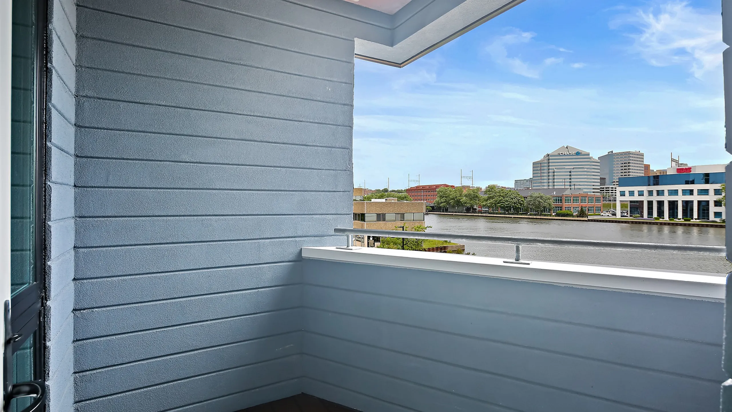 Charming balcony with sleek modern railings overlooking a tranquil river and city skyline.