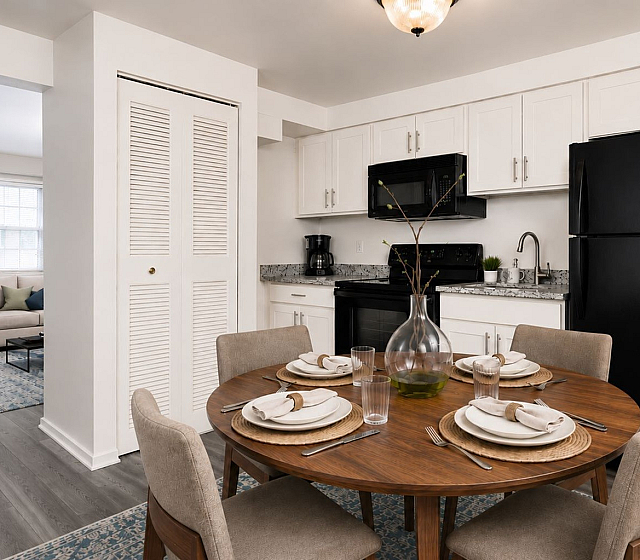 Chic apartment kitchen with modern appliances, cozy dining area, and inviting living space in view.