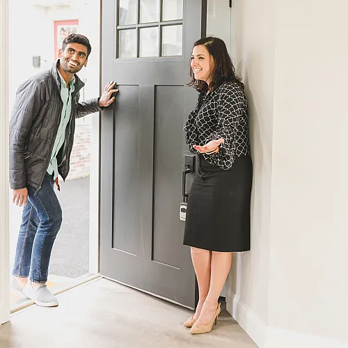 Welcoming entryway with smiling individuals entering a modern apartment, highlighting a bright and inviting atmosphere.