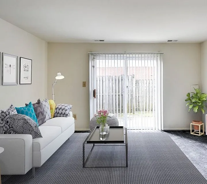 Bright and inviting living room featuring a cozy white sofa, stylish decor, and floor-to-ceiling sliding glass doors leading to a charming patio.