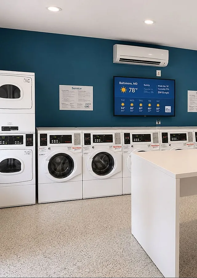 Modern laundry room featuring multiple efficient washing machines, sleek surfaces, and ample natural light for a clean, inviting atmosphere.