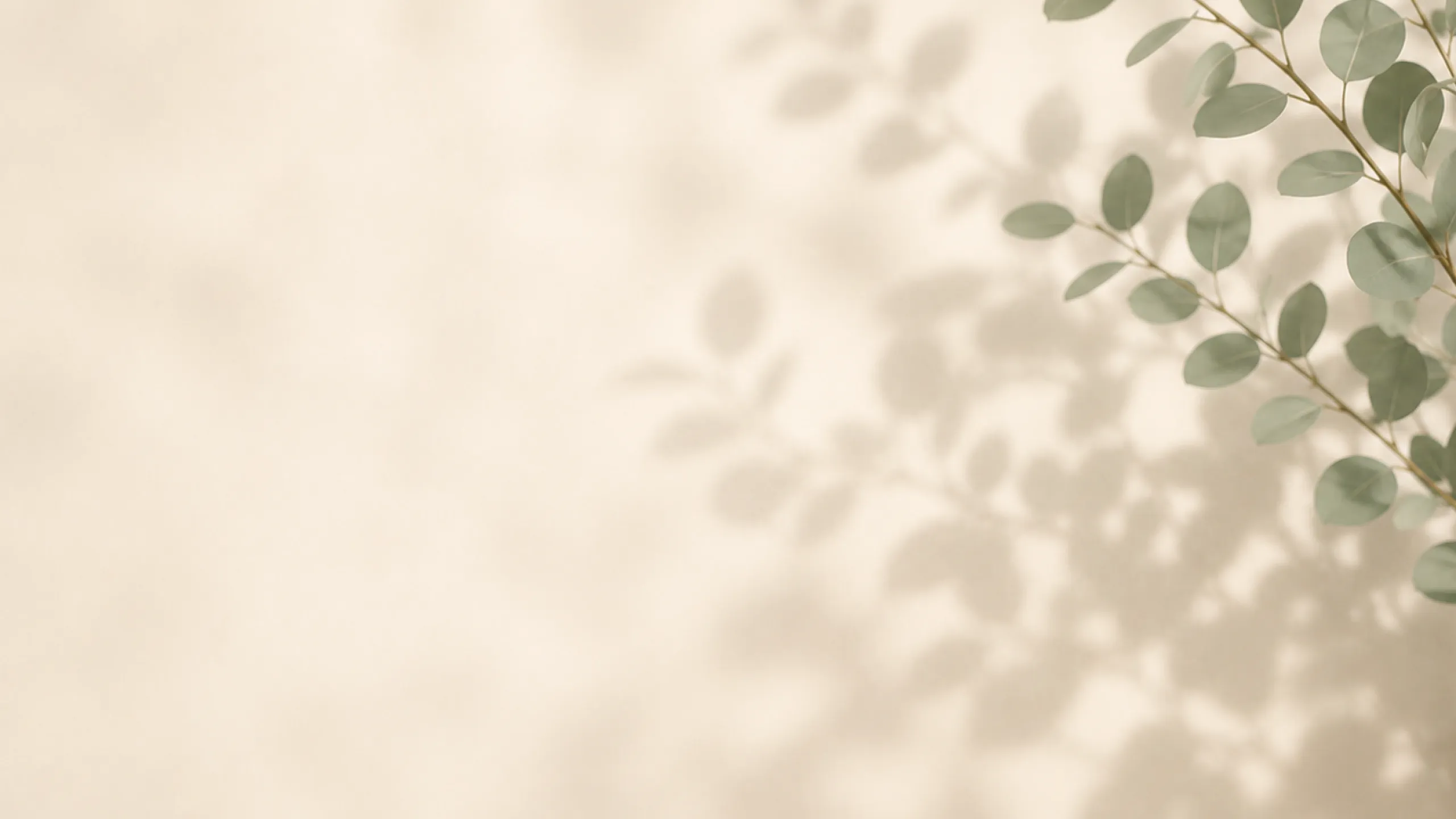 Elegant shadow of leafy branches against a subtle beige wall, creating a serene and natural ambiance.
