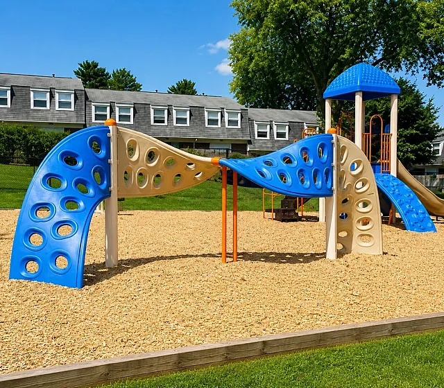 Charming playground surrounded by lush greenery, featuring modern climbing elements and slides, perfect for family fun in a safe, vibrant community.