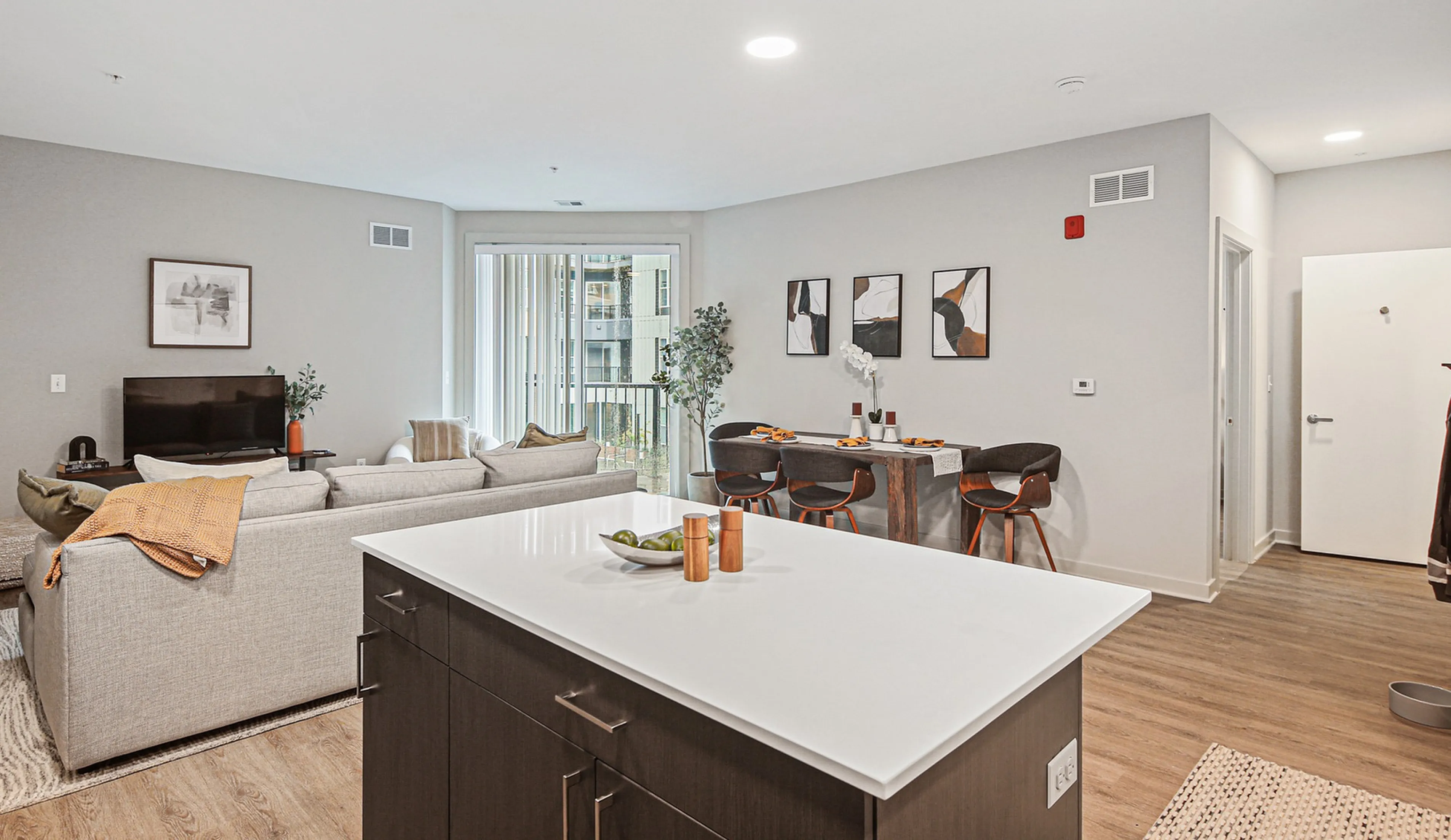 Bright and modern open-concept living space featuring a cozy living room, chic dining area, and sleek kitchen island with elegant decor.