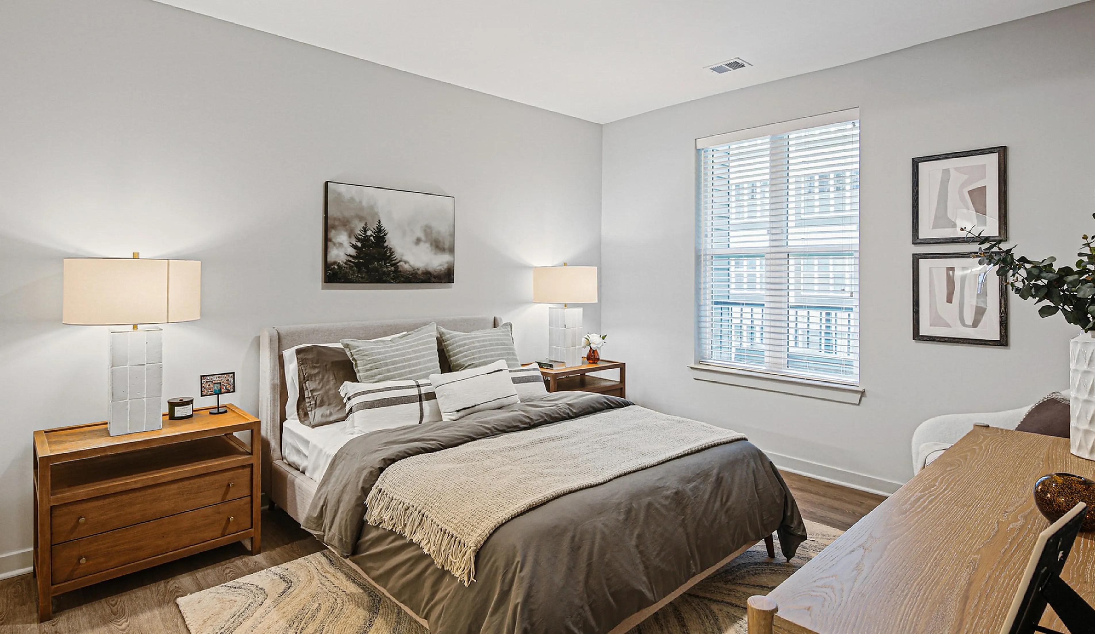 Inviting bedroom featuring a plush bed with cozy linens, stylish wooden nightstands, and warm lighting, complemented by modern wall art and large windows.