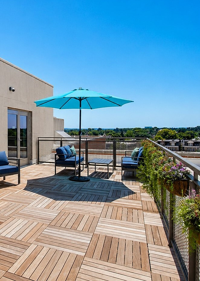 Contemporary rooftop terrace with stylish seating, vibrant blue umbrella, and stunning city views.