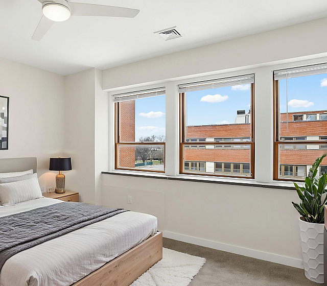 Bright and inviting bedroom with modern decor, large windows showcasing a beautiful city view, and a cozy king-sized bed.