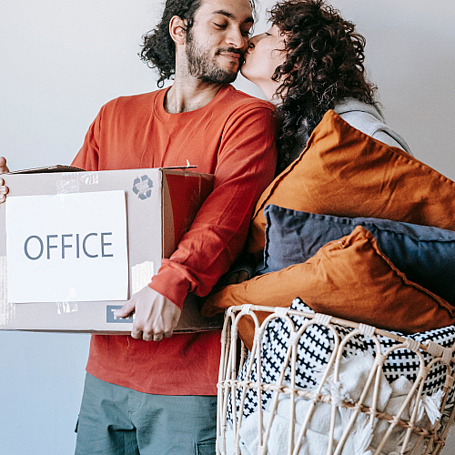 Happy couple moving into their new apartment, carrying boxes and pillows with excitement and joy.