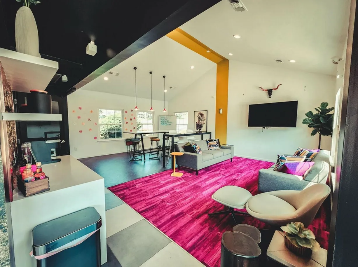Vibrant and modern living space featuring bold pink carpeting, sleek furniture, and contemporary decor with ample natural light.