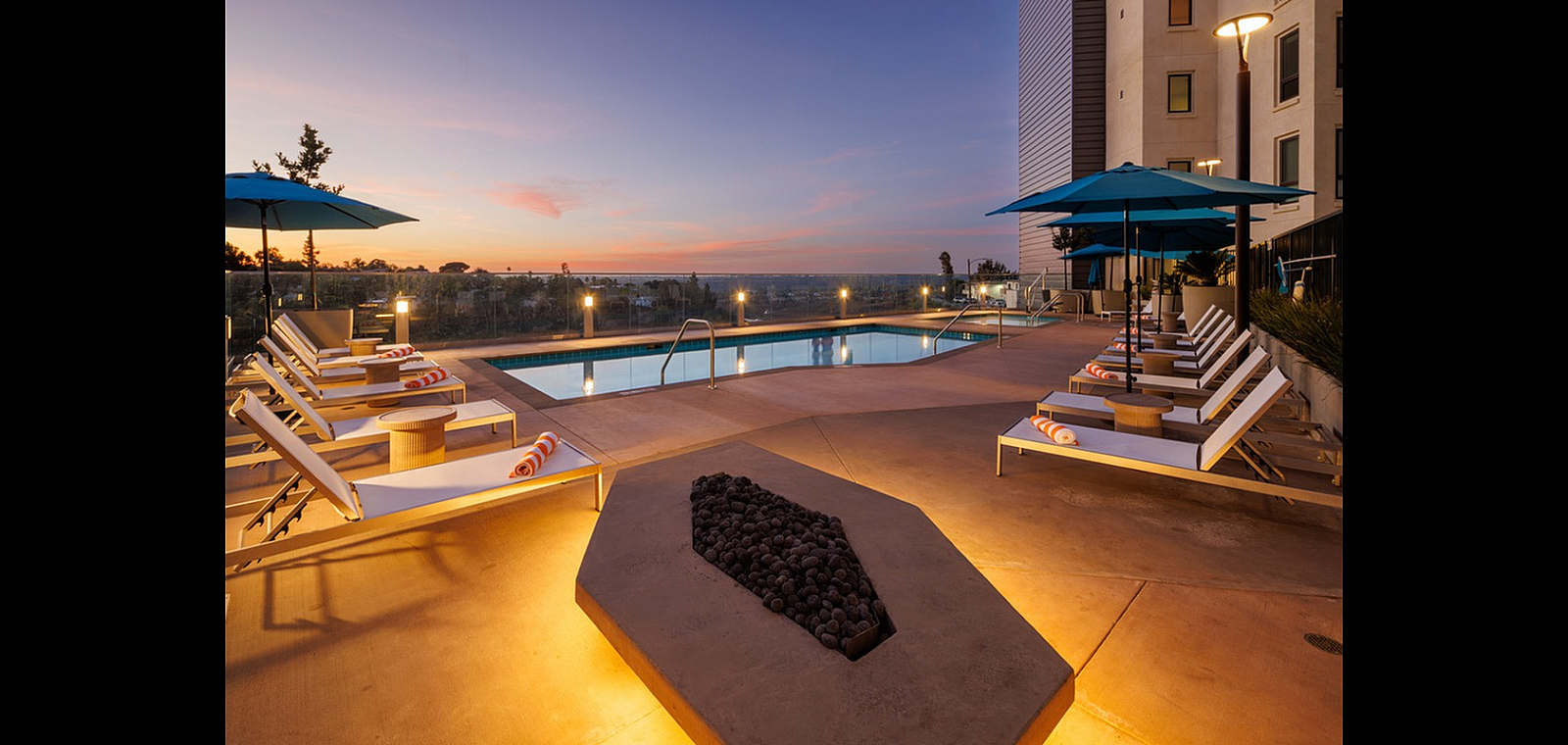 Luxurious sunset view by the pool with cozy lounge chairs and umbrellas, perfect for relaxation and enjoyment.