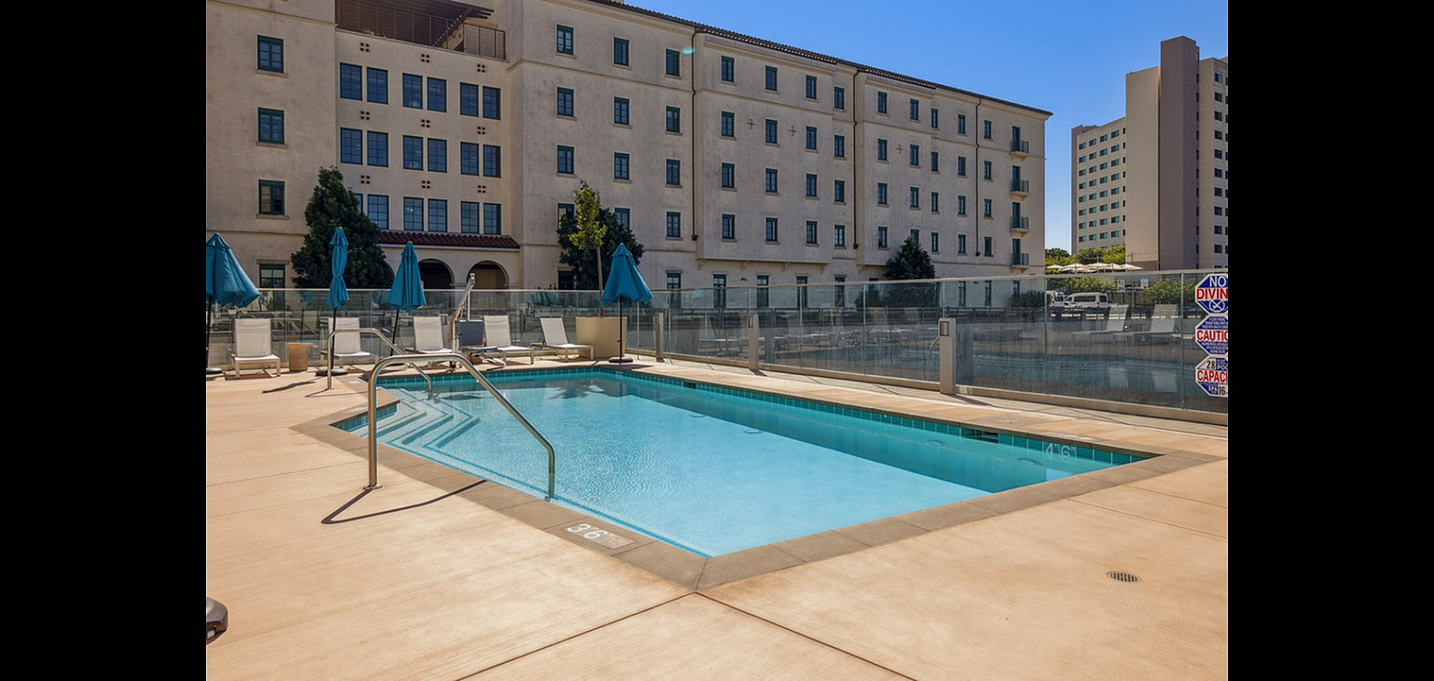 Chic outdoor pool area with modern loungers, surrounded by elegant architecture, offering a serene relaxation spot.