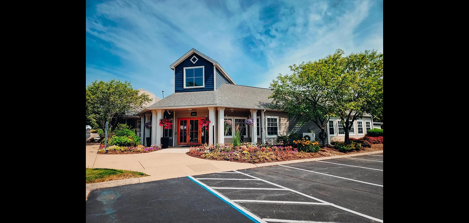 Charming residential building with vibrant landscaping and inviting entrance, under a clear blue sky.
