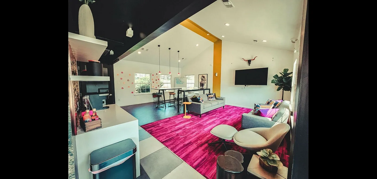 Vibrant and modern living room with bold pink accents, cozy seating, stylish furniture, and high ceilings creating a welcoming atmosphere.