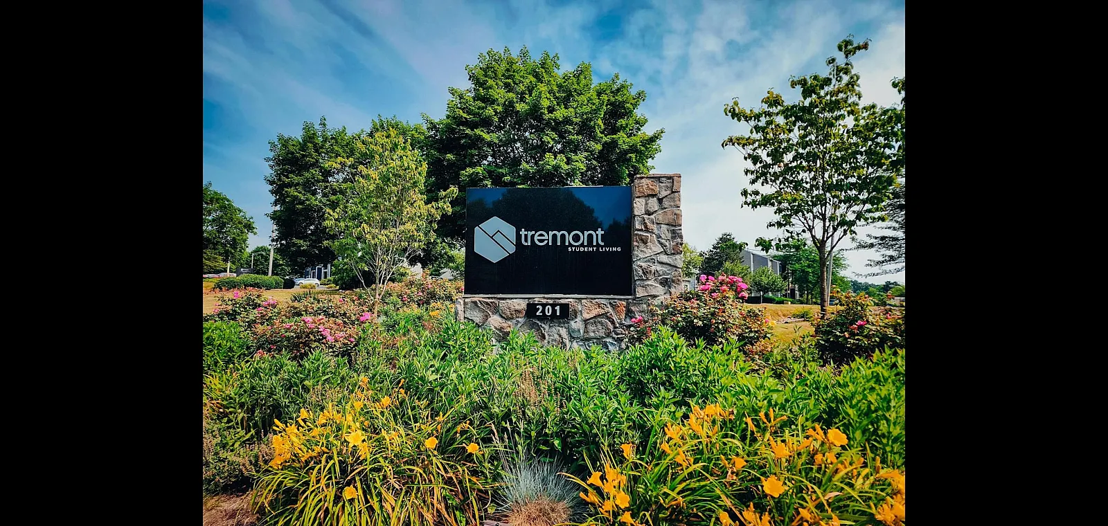 Inviting entrance to Tremont Student Living surrounded by vibrant gardens and lush greenery.