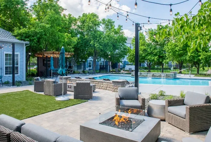 Inviting outdoor space featuring a cozy fire pit, stylish patio furniture, and a sparkling pool under string lights.
