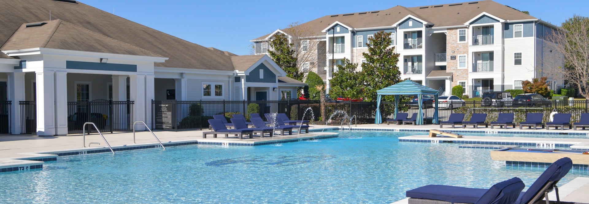 the hudson statesboro student housing pool view with lounge chairs and clubhouse entrance