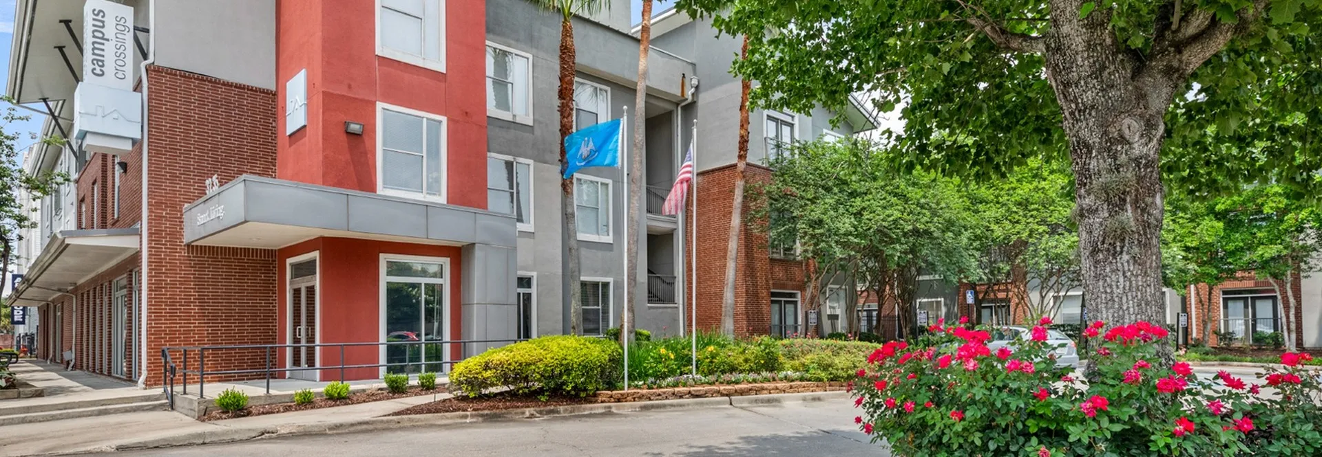 entrance to leasing office with flowers and flags campus crossings on highland baton rouge