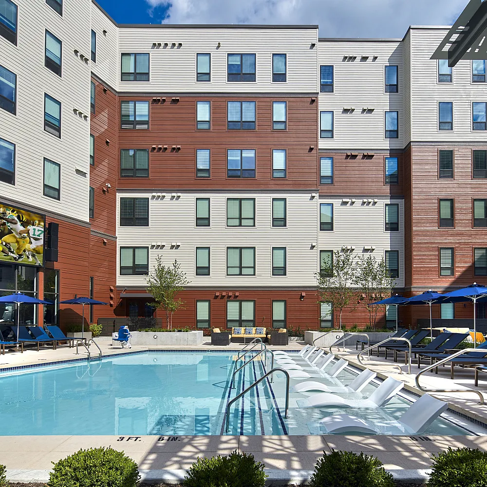the yard on south main ann arbor pool area with sun chairs, table, umbrellas and big screen tv