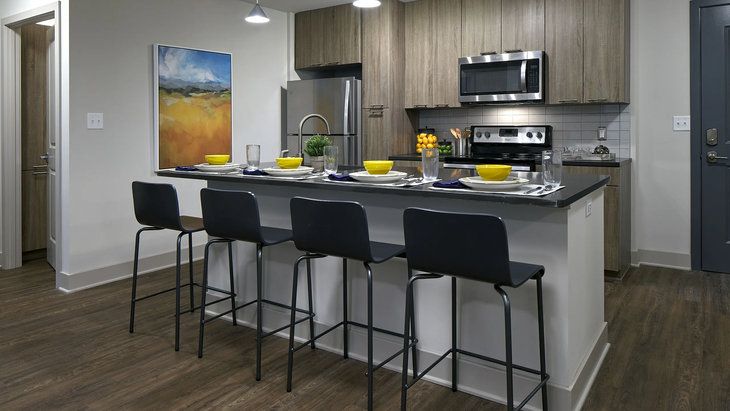 six11 ann arbor model unit kitchen area with full island, stools, sink, and stainless steel appliances.