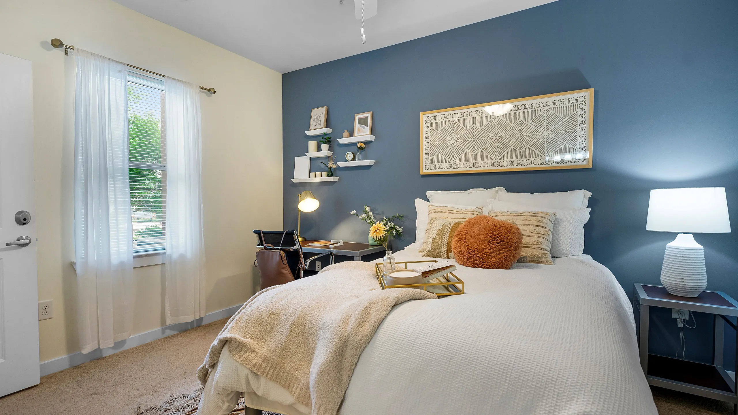 campus crossings briarcliff 2 bedroom model unit with full sized bed, desk, and end table.