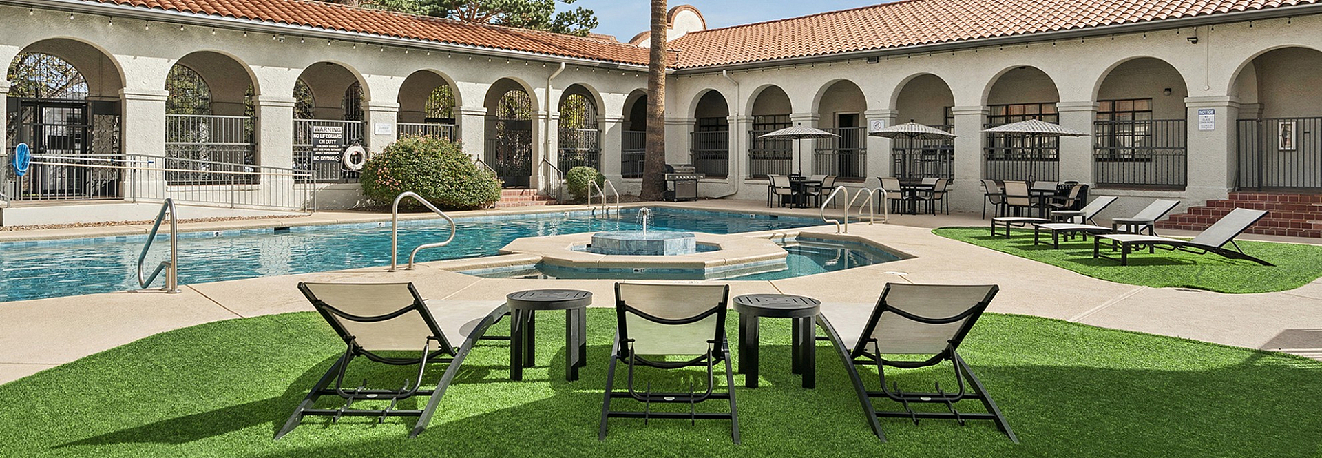 Inviting outdoor pool area with lush greenery, sun loungers, and charming arched architecture, perfect for relaxation.