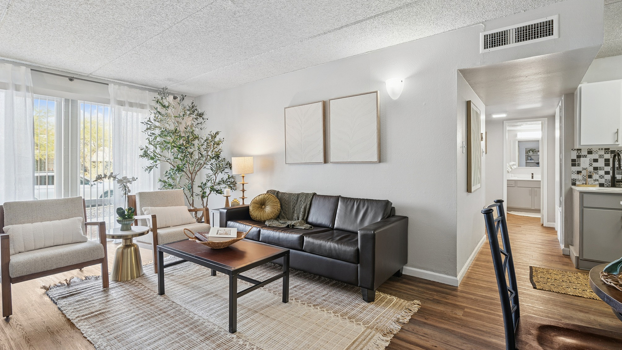 Elegant living room with stylish decor, featuring a sleek black leather sofa, cozy armchairs, and a natural light-filled ambiance.