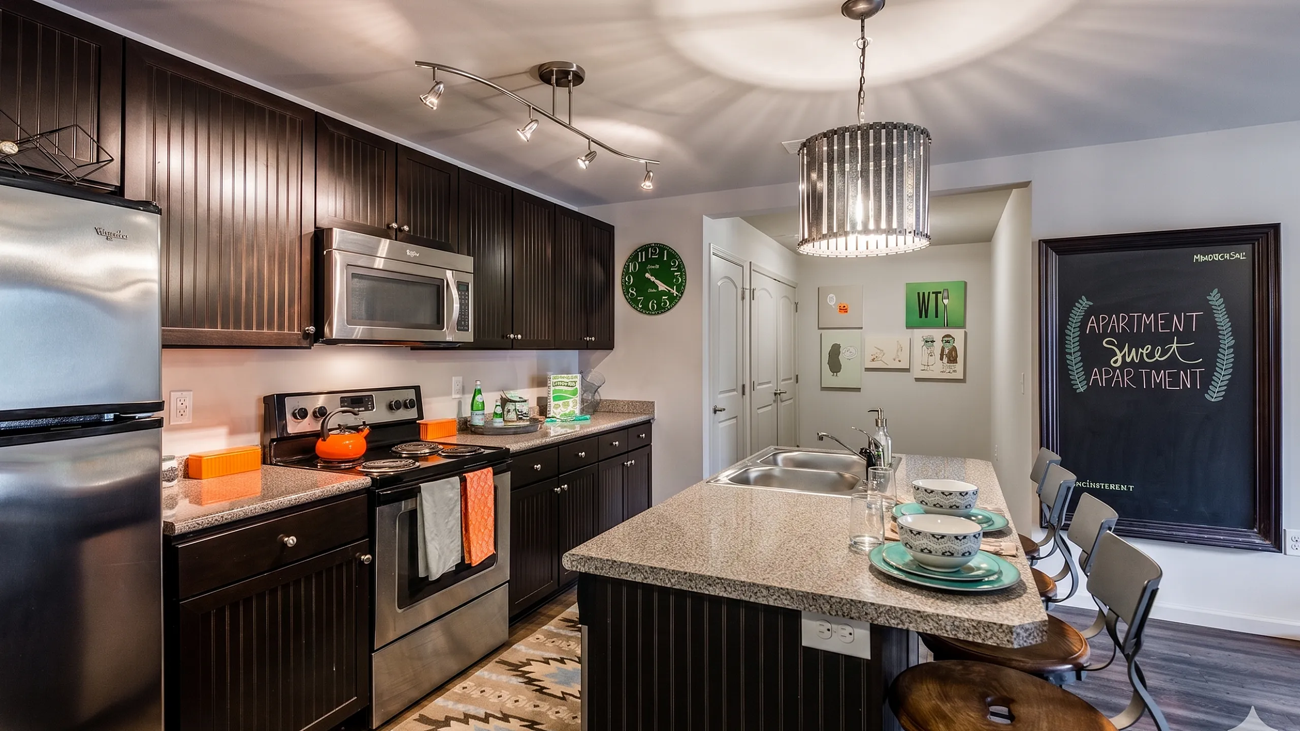 Chic apartment kitchen featuring stylish dark cabinets, stainless steel appliances, and a cozy breakfast bar with elegant lighting.