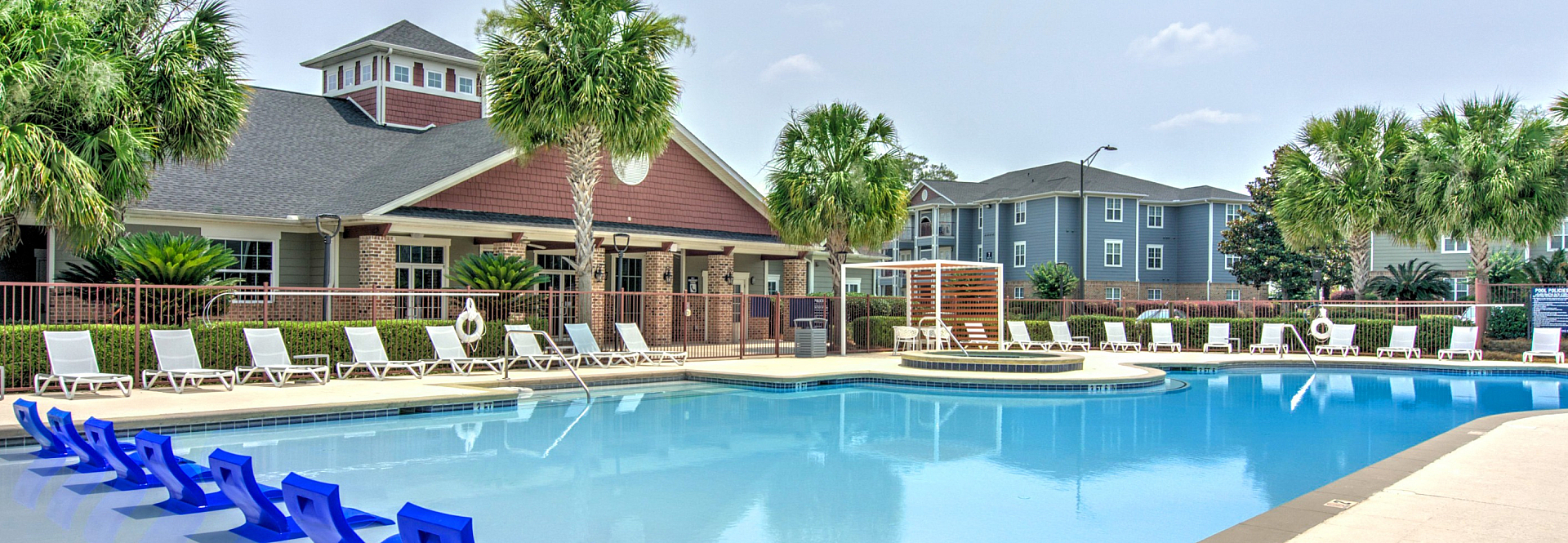 Inviting poolside oasis featuring elegant blue lounge chairs surrounded by lush palm trees and chic apartment buildings, perfect for relaxation.