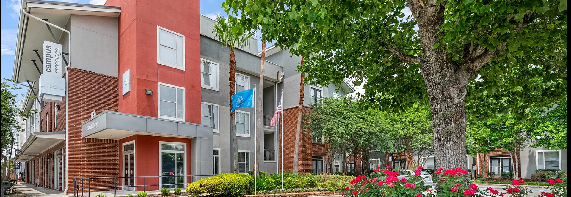 Inviting apartment complex with modern architecture, surrounded by lush greenery and vibrant flower gardens.
