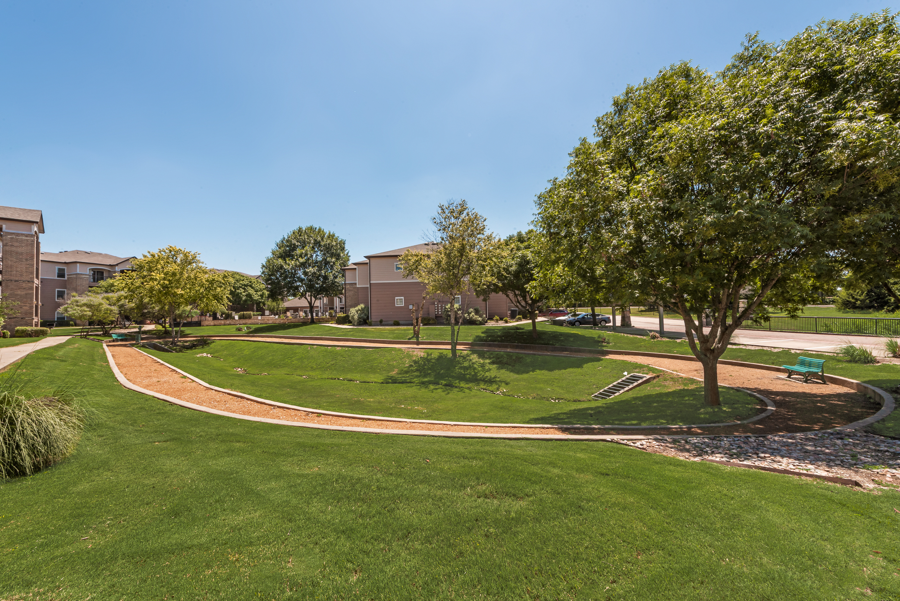 Charming apartment complex nestled amid lush green landscapes and walking paths, offering a serene and welcoming atmosphere.