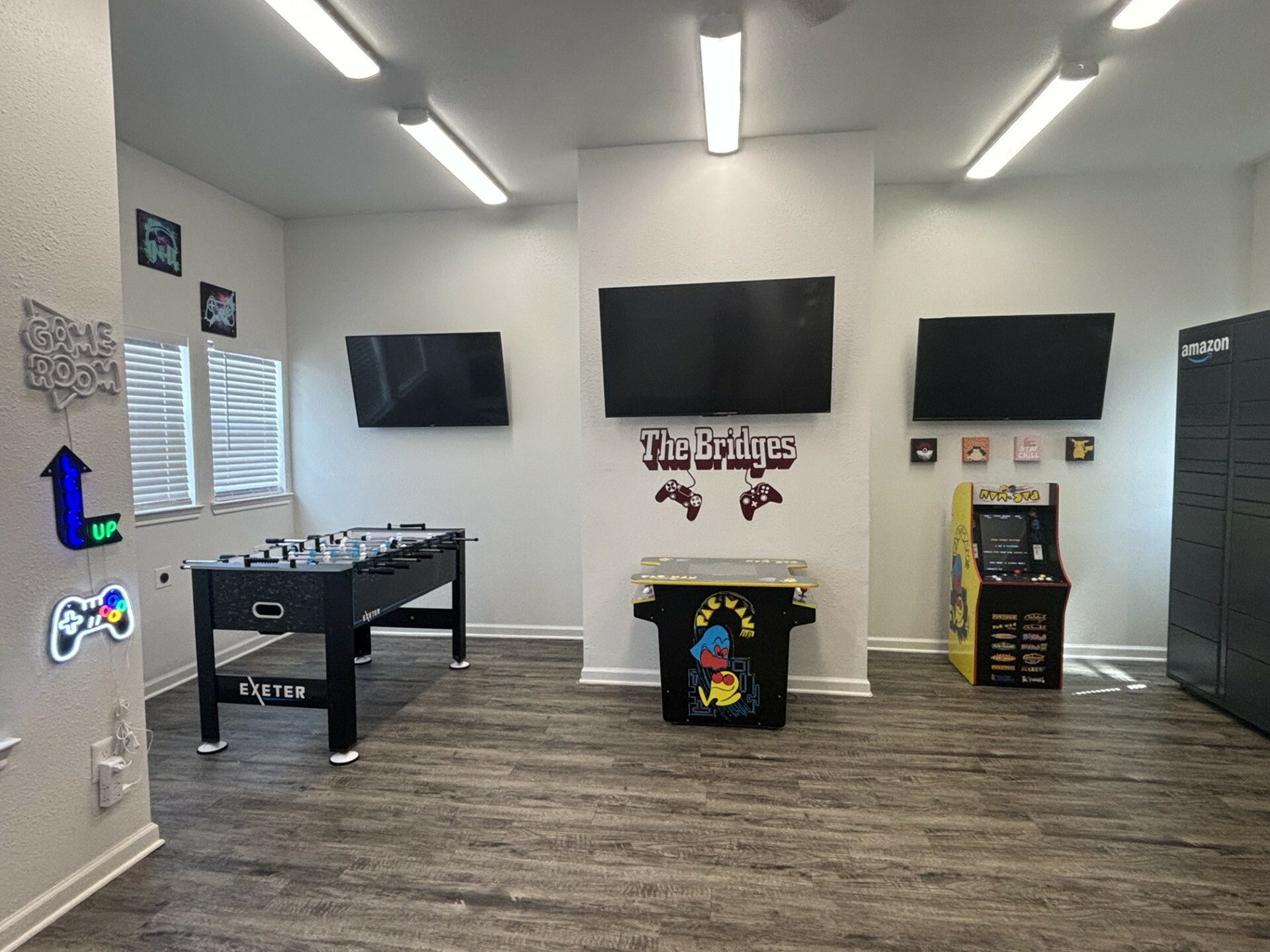 Vibrant game room featuring modern foosball table, retro arcade machine, and dual wall-mounted TVs with stylish decor.