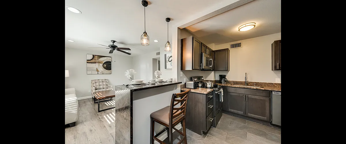 Contemporary open-concept kitchen and living area with sleek modern design, featuring granite countertops and elegant lighting.