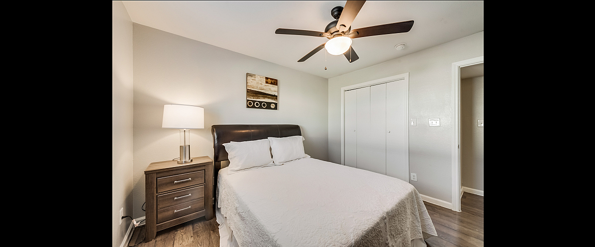 Cozy bedroom featuring a plush bed, modern bedside table with a sleek lamp, and chic decor, creating a tranquil retreat.