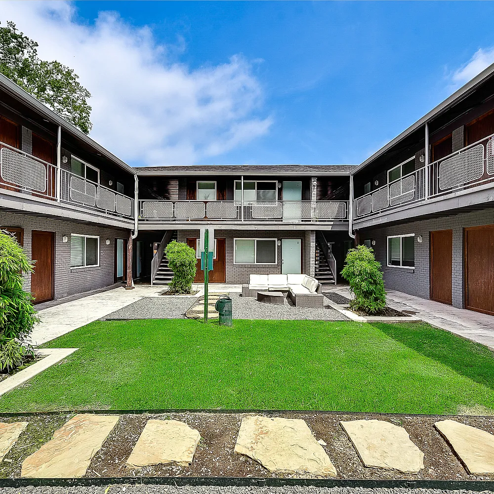 Charming courtyard apartment complex featuring modern architecture with lush greenery and outdoor seating.