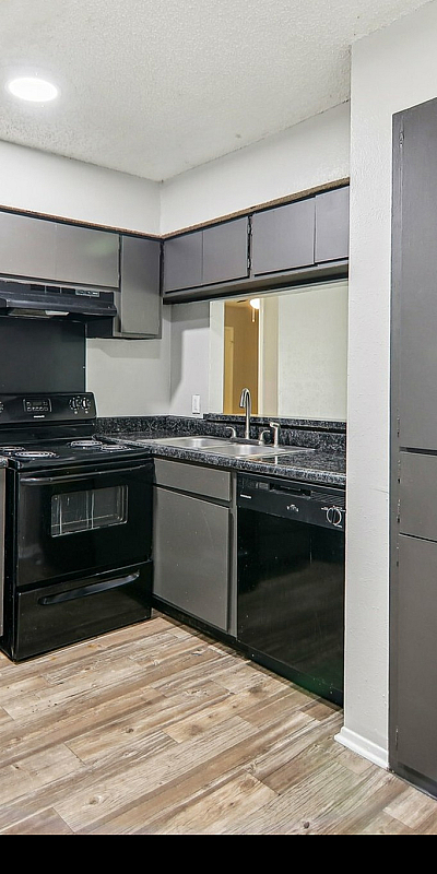 Modern kitchen with sleek black appliances, ample cabinetry, and elegant dark countertops, perfect for cooking and entertaining.