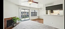 Bright and airy living space with a modern ceiling fan, cozy fireplace, and large sliding glass doors leading to a balcony, offering delightful views and natural light.