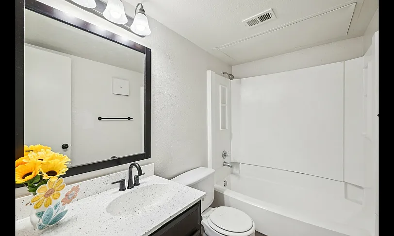 Bright and modern bathroom featuring a sleek vanity with elegant lighting and cheerful sunflowers, perfect for relaxation.