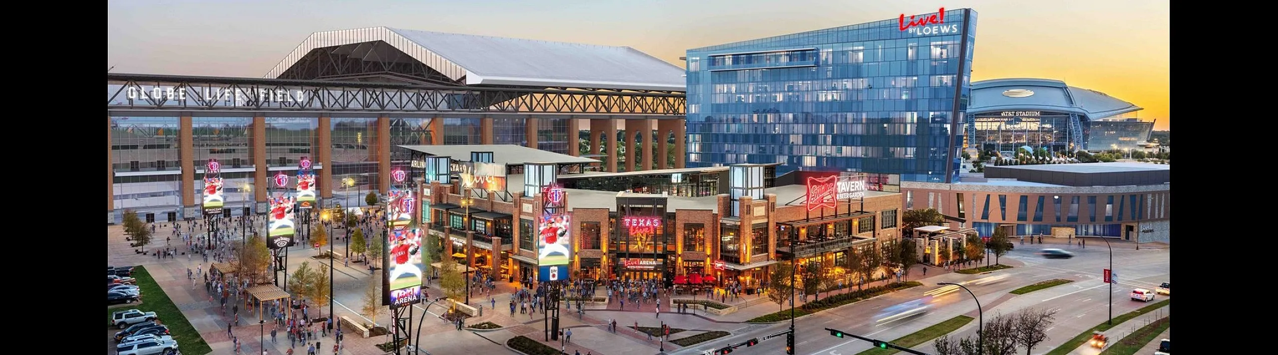 Vibrant evening view of a bustling entertainment district featuring a modern mixed-use complex, adjacent to iconic architectural landmarks.