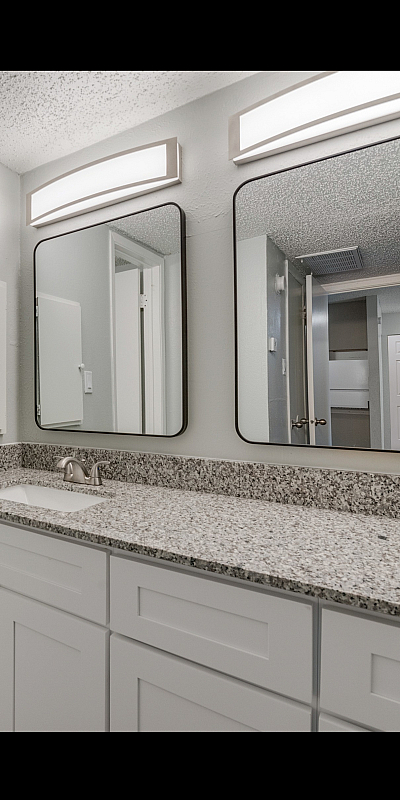 Modern bathroom with sleek granite countertops, dual square mirrors, and stylish lighting, offering a fresh and contemporary design.