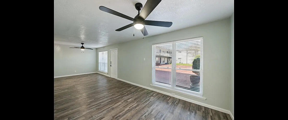 Modern apartment with sleek wooden flooring, large windows allowing natural light, and ceiling fans for enhanced comfort.