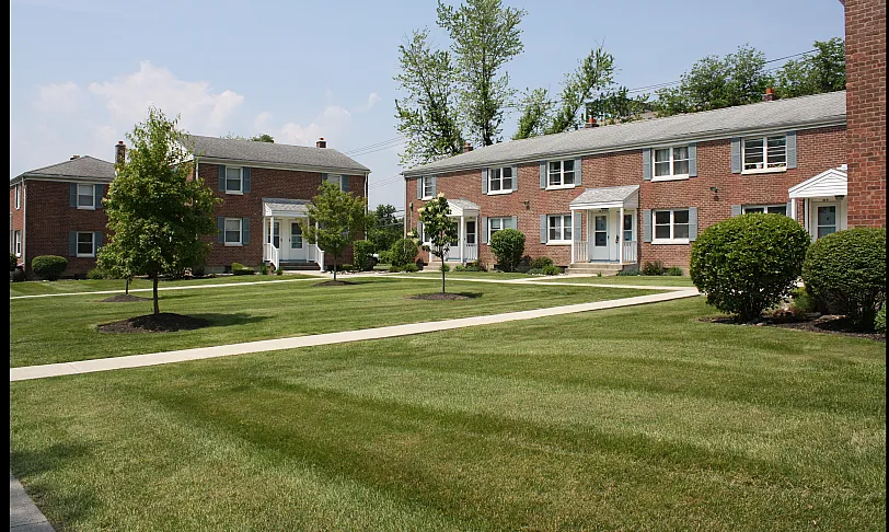 Charming brick apartment buildings with lush green lawns and inviting walkways, perfect for serene living.