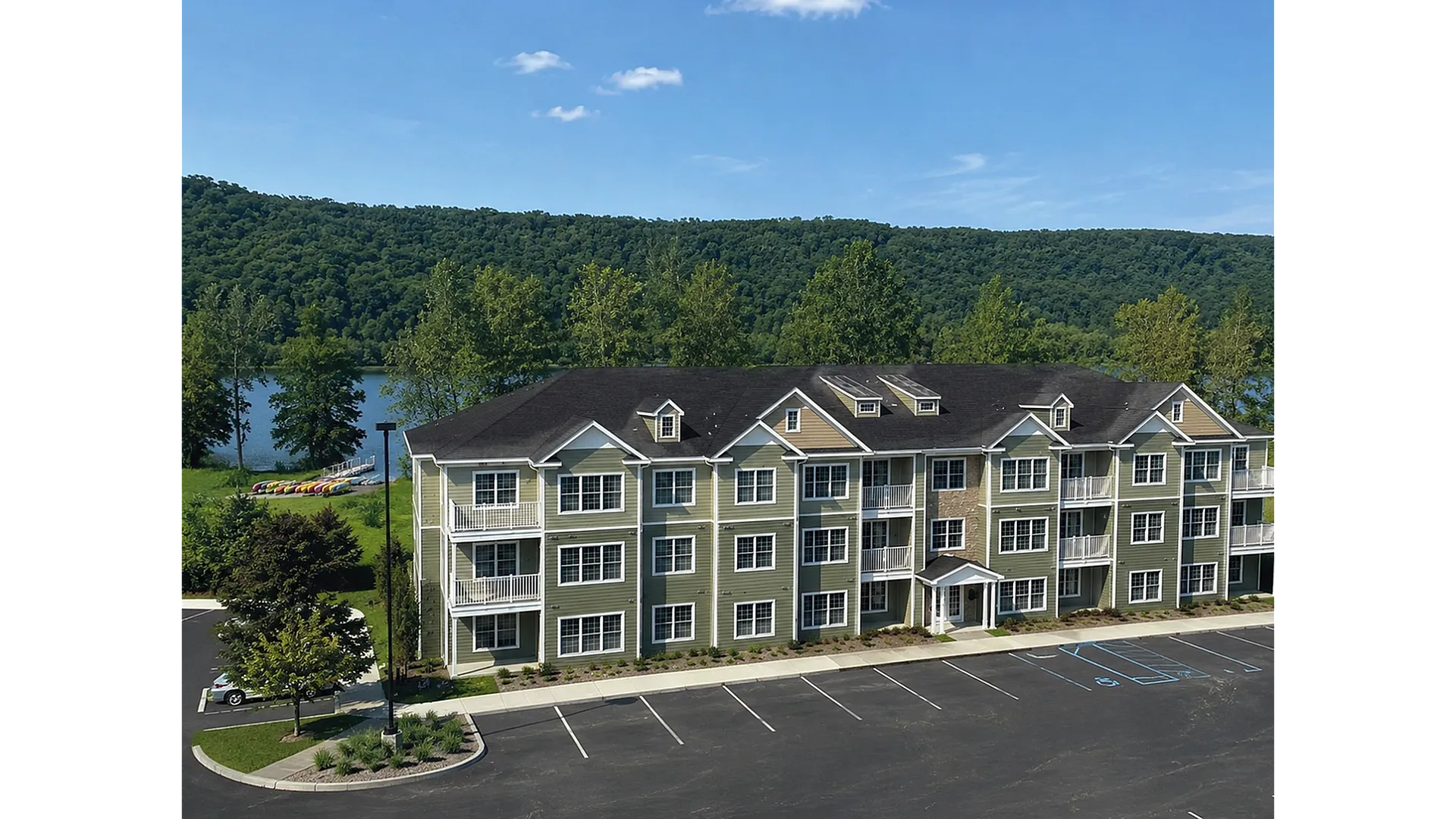 Charming lakeside apartment building with scenic views, featuring green exterior and white balconies nestled among lush greenery.