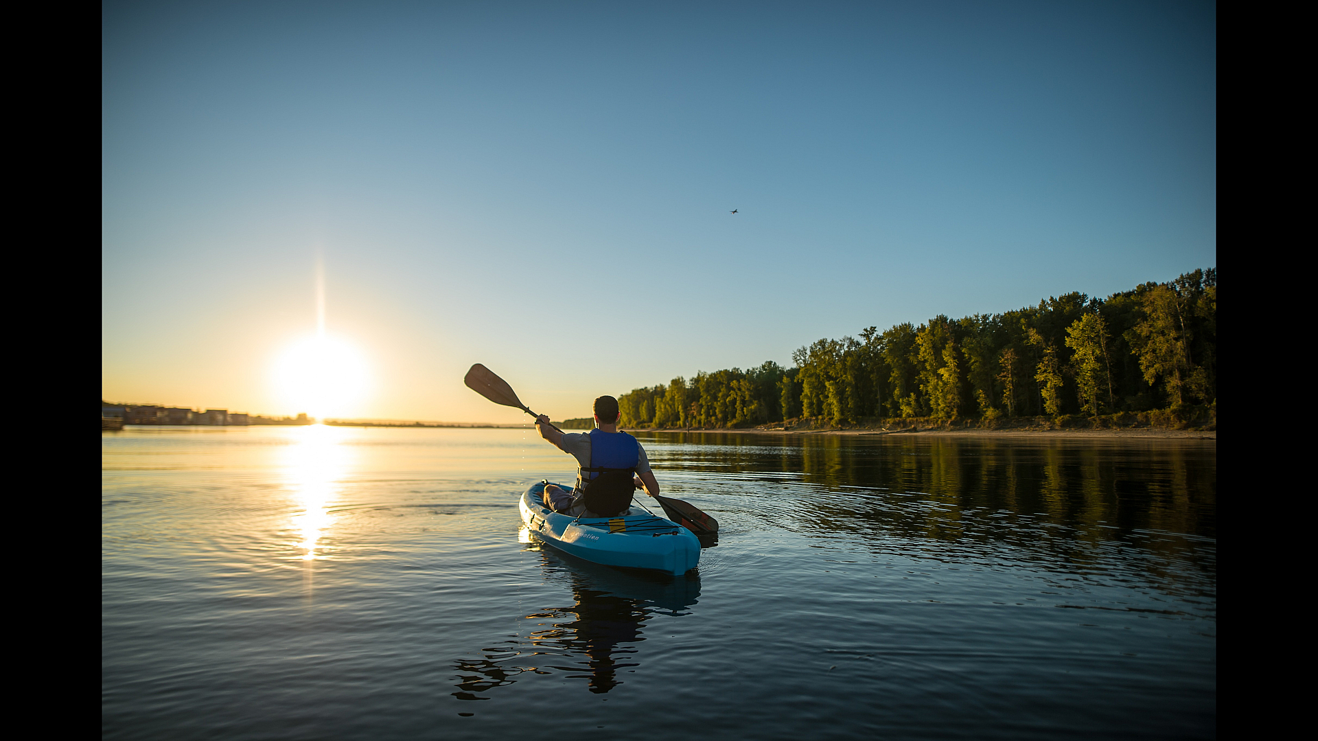 Serene sunset kayaking on a tranquil lake surrounded by lush greenery, perfect for nature enthusiasts.