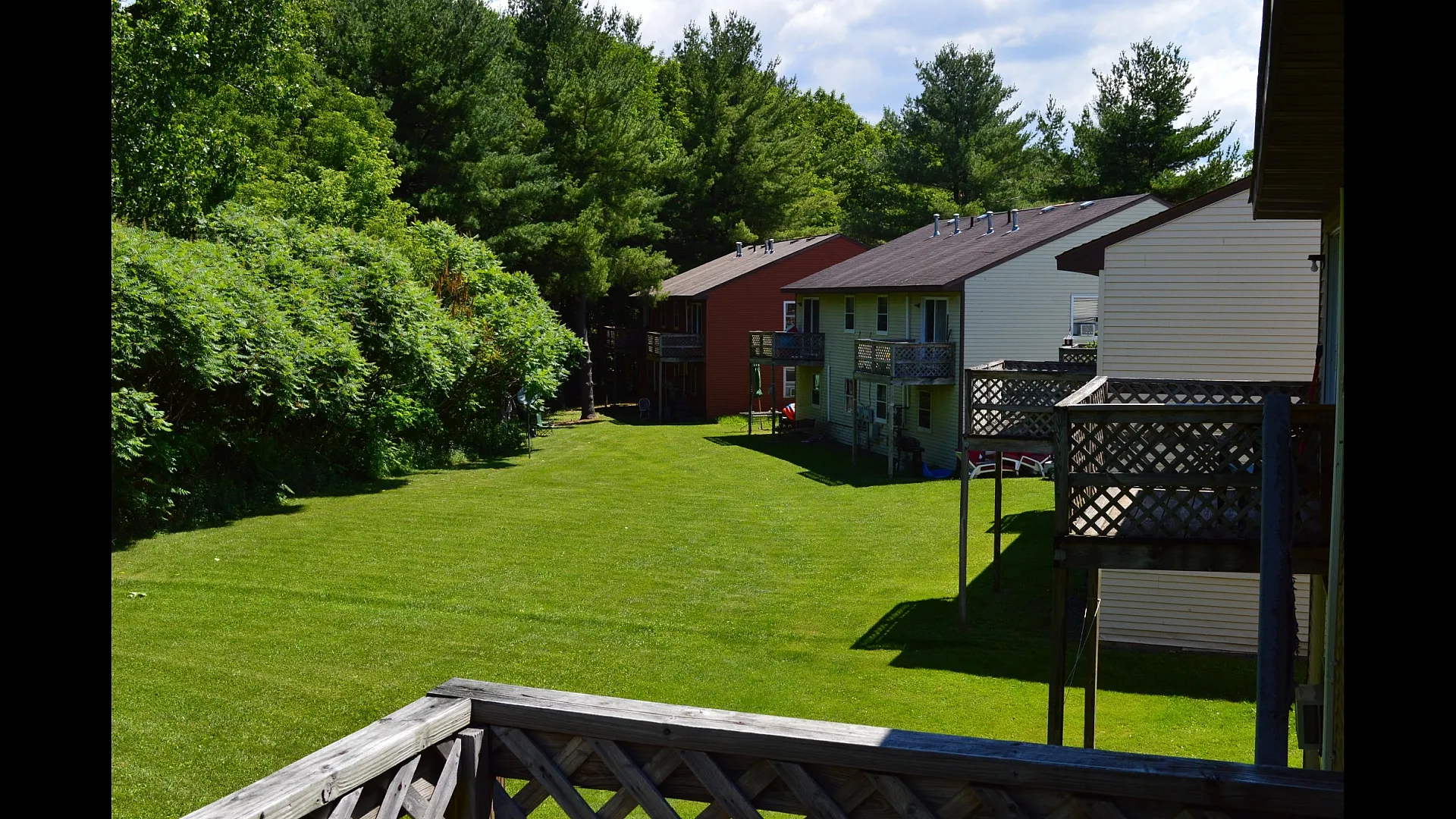Charming view of townhouses with private balconies overlooking lush green lawns and surrounded by vibrant trees, offering a serene and picturesque living environment.